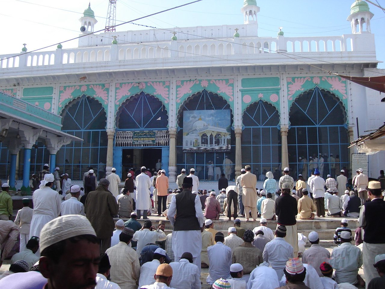 Pilgrims at prayer before a white marble mosque